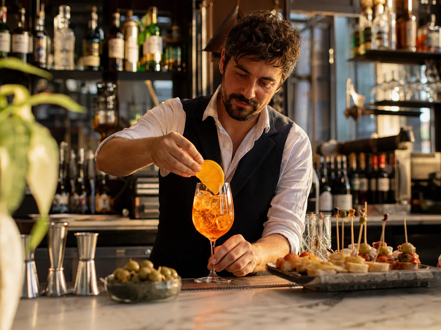 Barman prepara uno spritz al bancone di un locale durante l’aperitivo